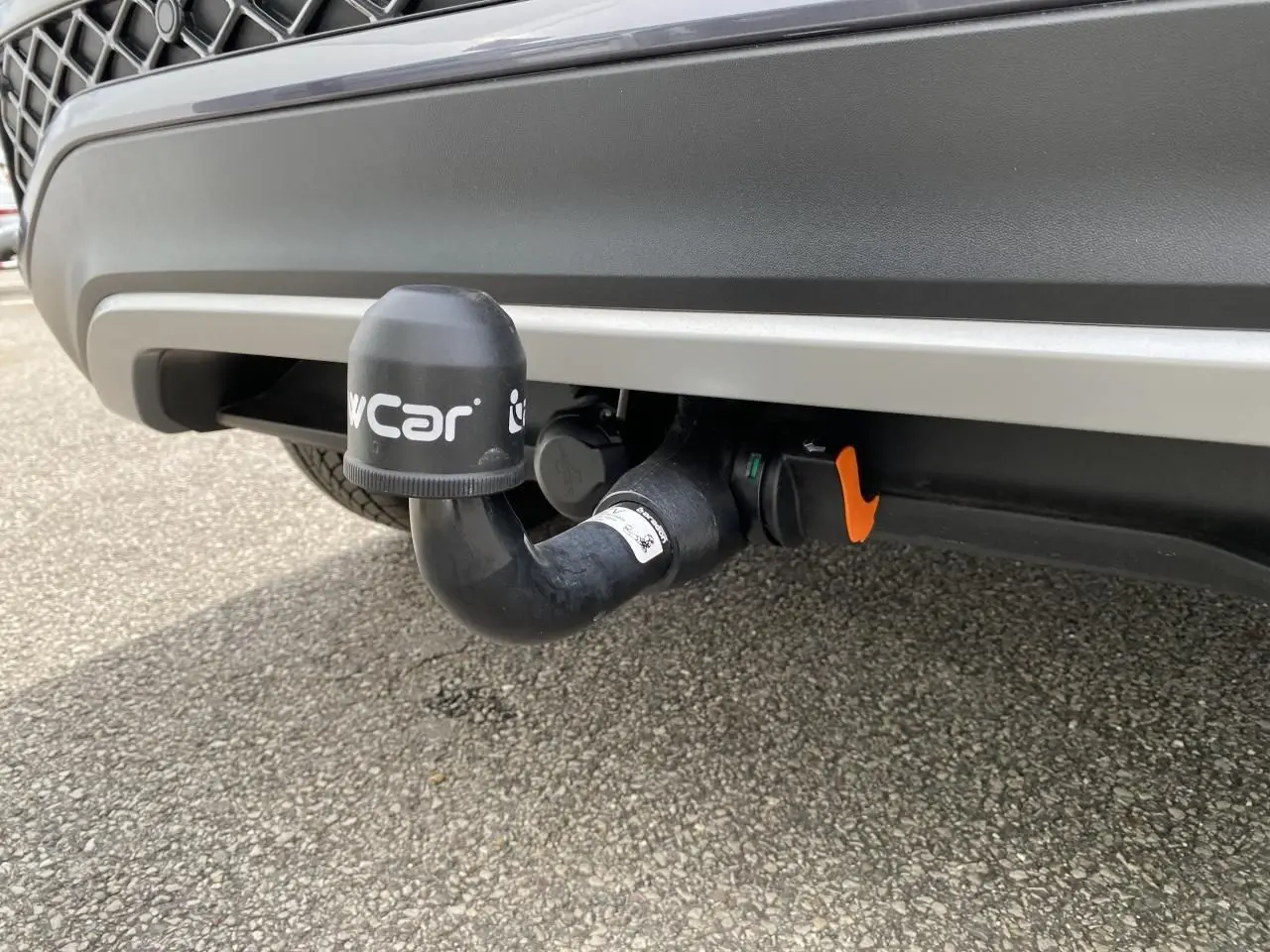 Gros plan sur l'attelage amovible noir sous le pare-chocs arrière gris du Volkswagen T-Cross 2024.
