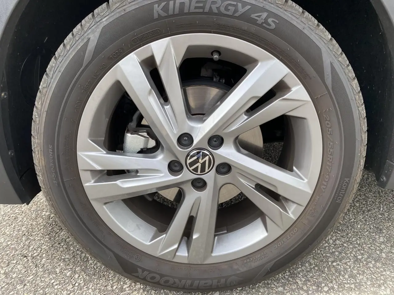 Gros plan sur la roue avant droite du Volkswagen T-Cross gris avec jante alliage et logo VW au centre.
