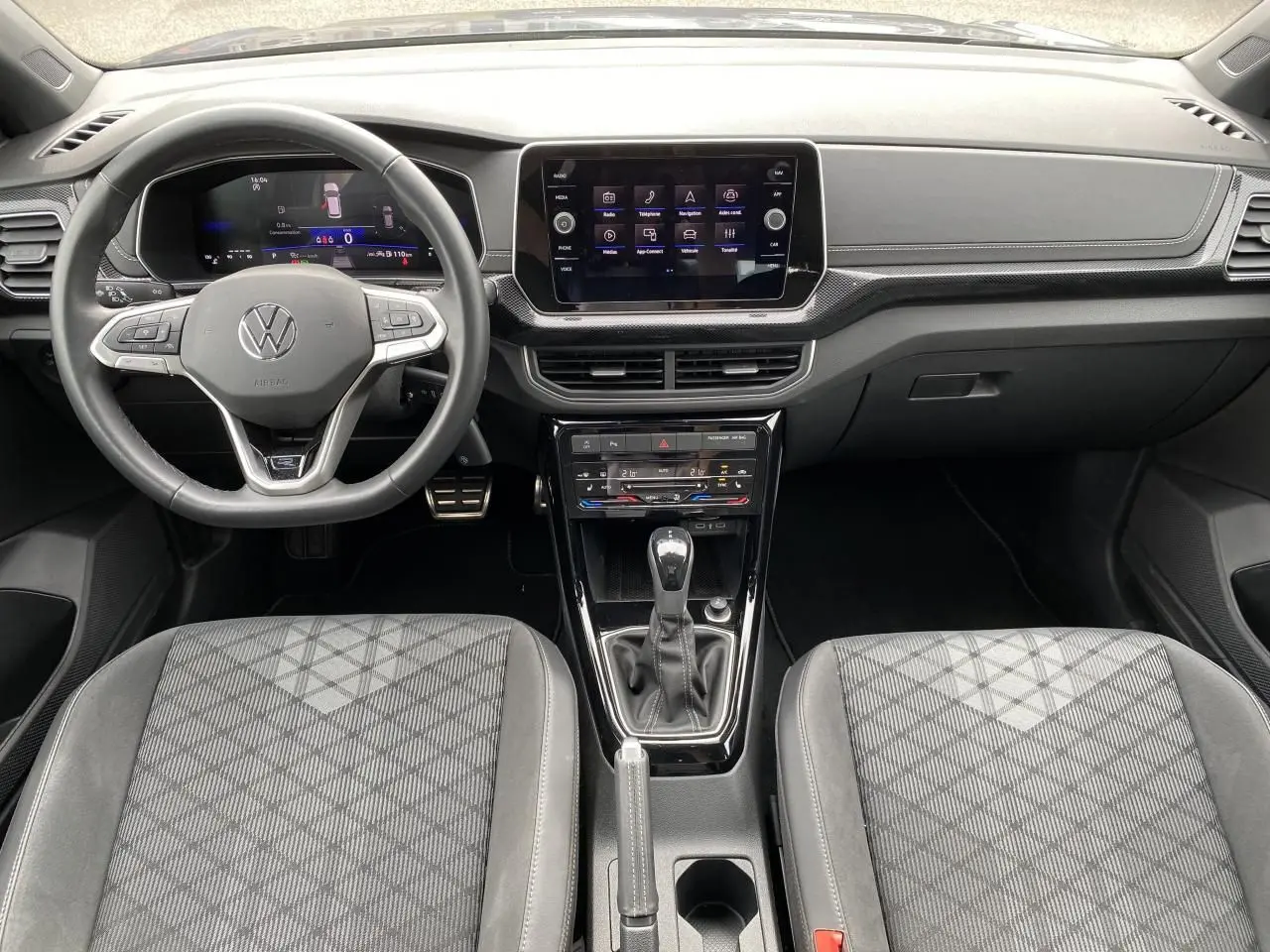 Vue intérieure frontale du Volkswagen T-Cross gris 2024, avec tableau de bord digital et volant multifonction cuir.