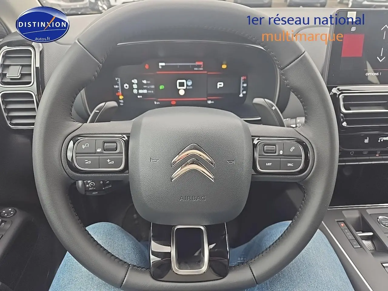 Vue rapprochée du volant cuir noir du Citroën C5 Aircross 2025 avec tableau de bord numérique et commandes intégrées.