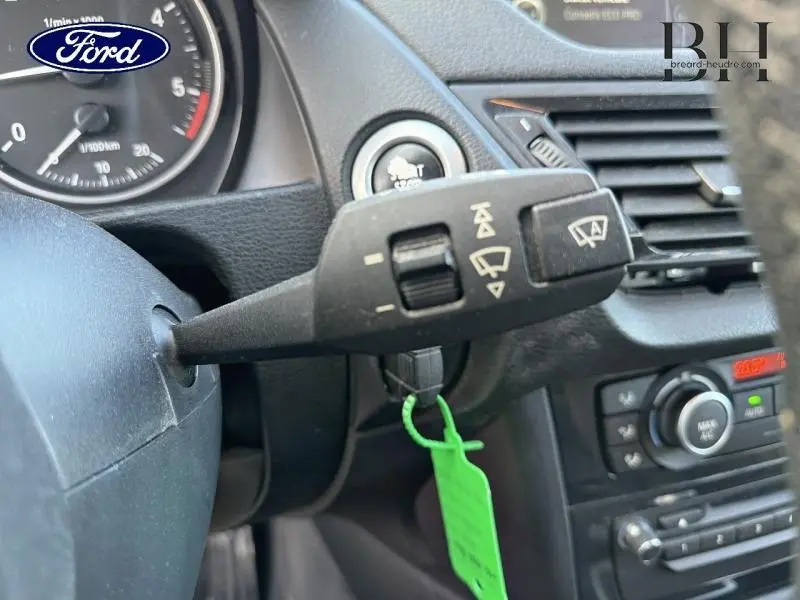 Gros plan sur la commande d’essuie-glace et le tableau de bord noir du BMW X1 xDrive25dA Mineralgrau, intérieur moderne et fonctionnel.