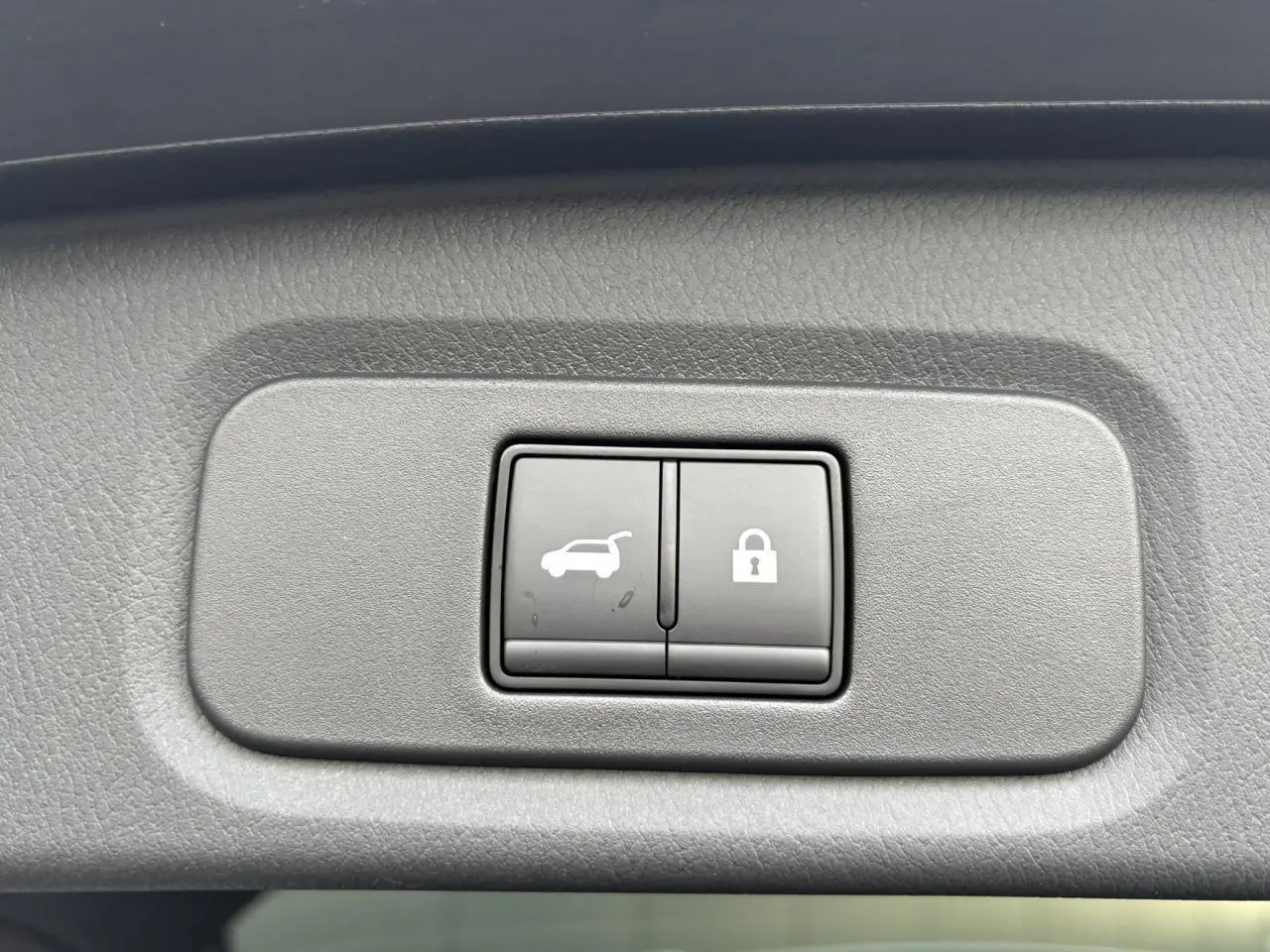 Gros plan sur les boutons d'ouverture électrique du hayon et de verrouillage, intérieur gris du Nissan Qashqai 2025.