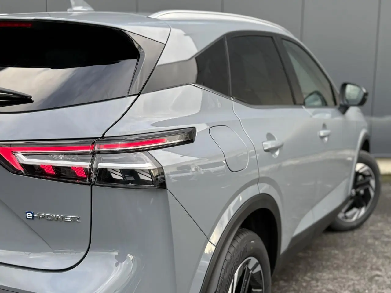 Vue 3/4 arrière droite du Nissan Qashqai III e-Power gris Ceramic avec feux arrière LED et badges distinctifs e-POWER.