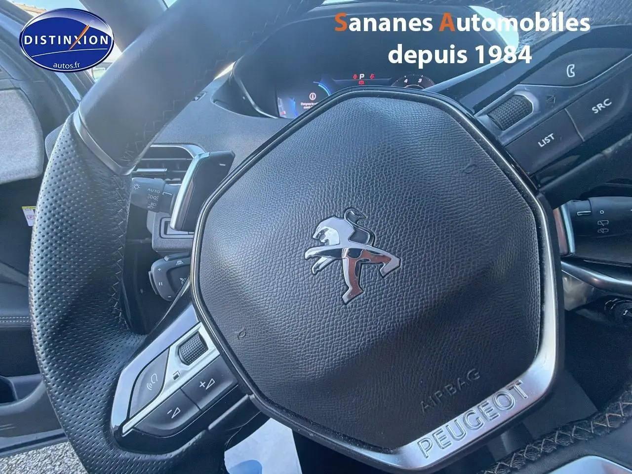 Gros plan sur le volant cuir perforé du Peugeot 3008 bleu 2023 avec logo lion et commandes intégrées.