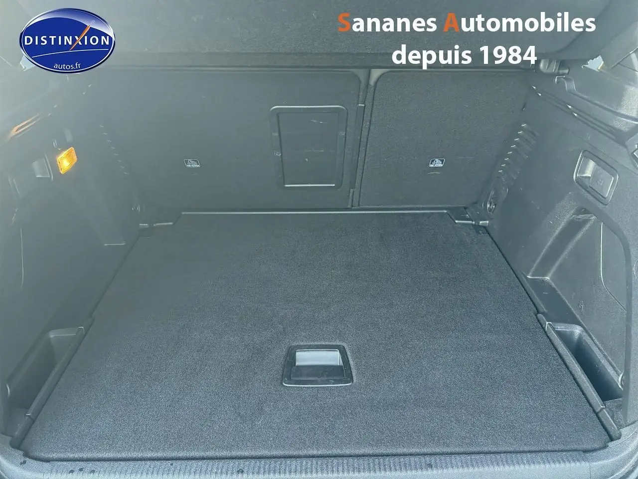 Vue plongeante sur le coffre spacieux et plat du Peugeot 3008 2023, finition GT, avec banquette rabattue et tapis noir.