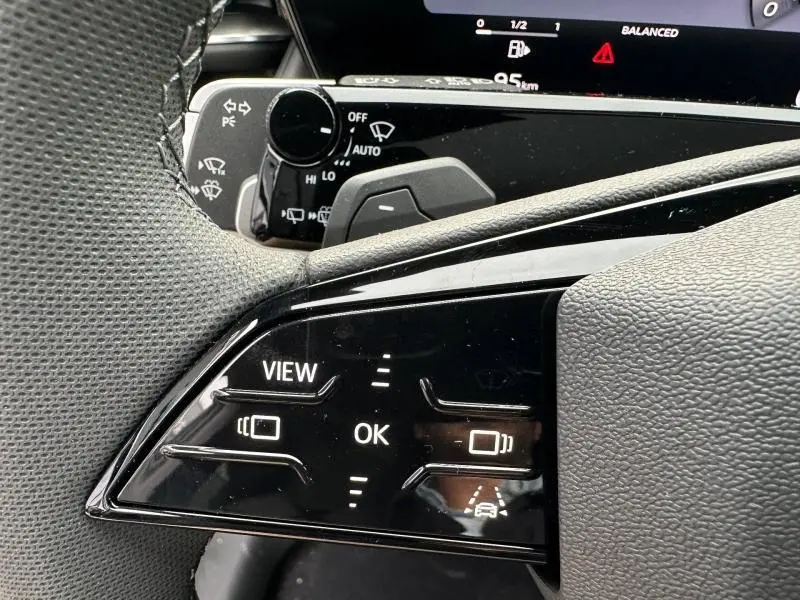 Gros plan sur les commandes au volant noir du côté gauche de l'Audi Q3 2026, avec affichage digital en arrière-plan.