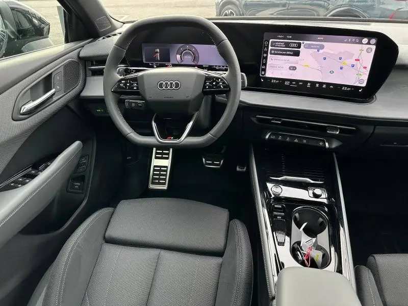 Vue intérieure avant de l'Audi Q3 2.0 TDI 2026, tableau de bord noir avec écran tactile et volant multifonction cuir.