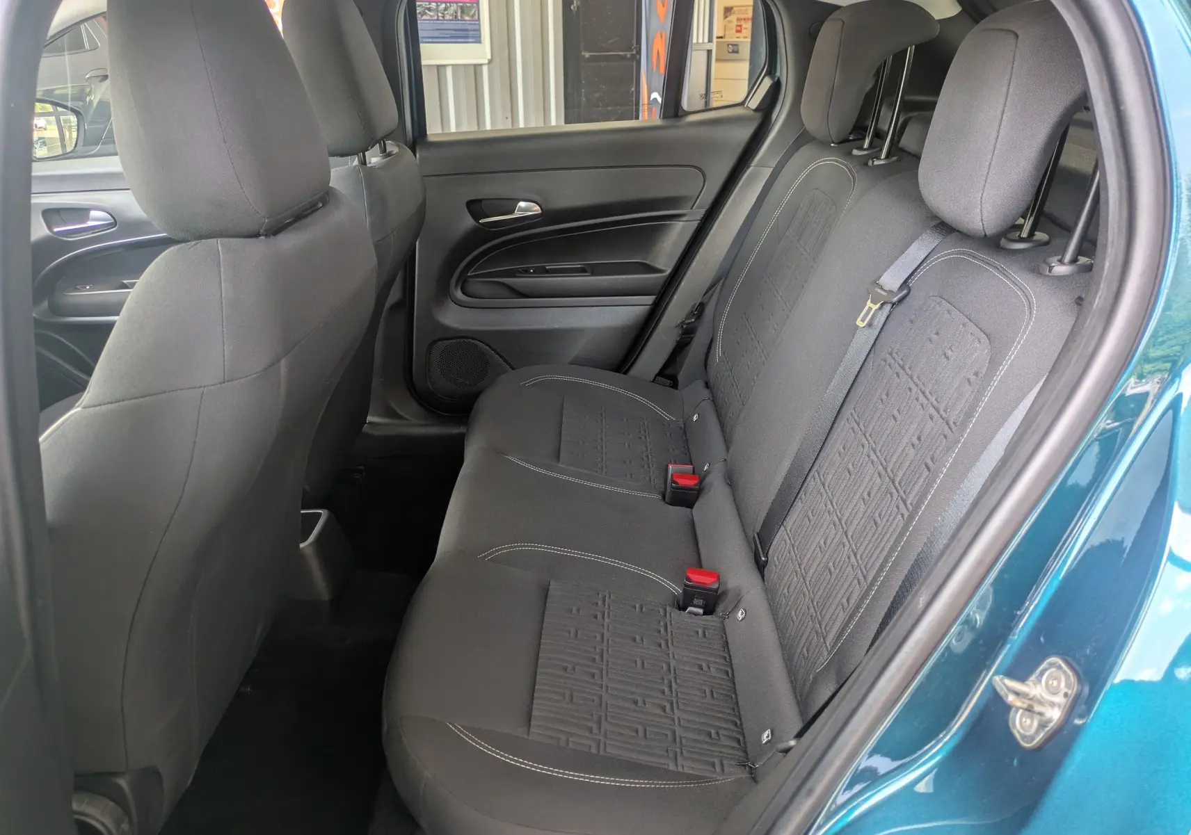 Vue intérieure côté droit des sièges arrière noirs avec motifs sur une FIAT 600 bleu Sea of Italy 2025.