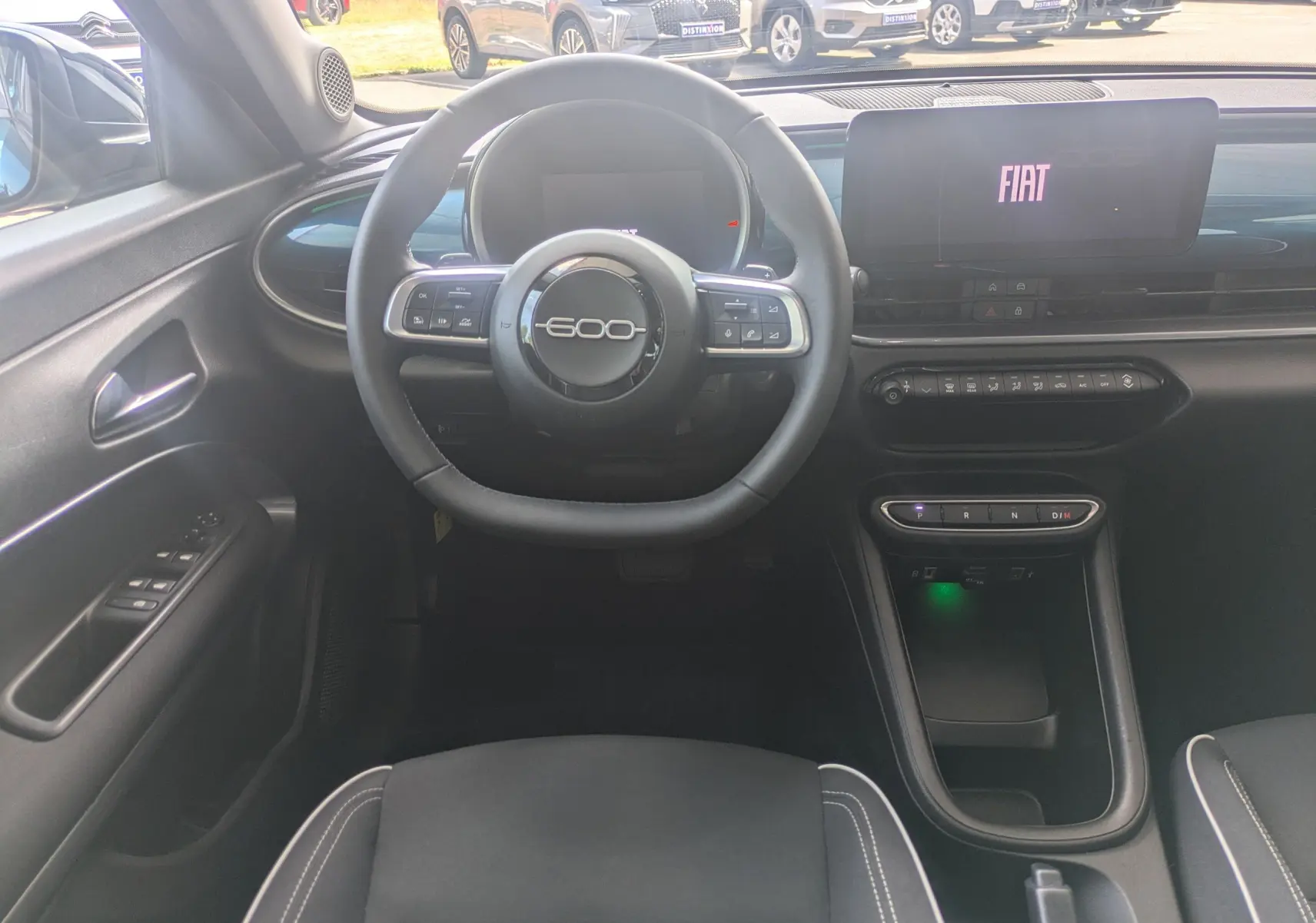 Vue intérieure centrée sur le volant et le tableau de bord numérique de la FIAT 600 1.2 Hybrid 2025, finition noire.