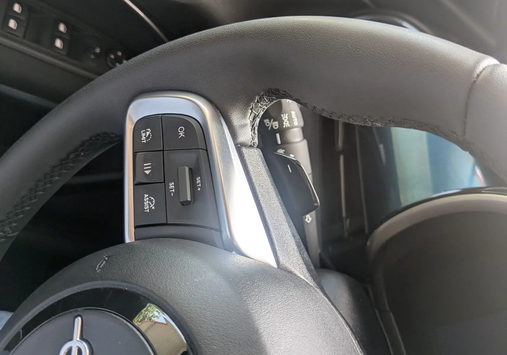 Gros plan sur le volant noir du Fiat 600 1.2 Hybrid 2025, avec commandes intégrées et partie de la portière côté gauche visible.