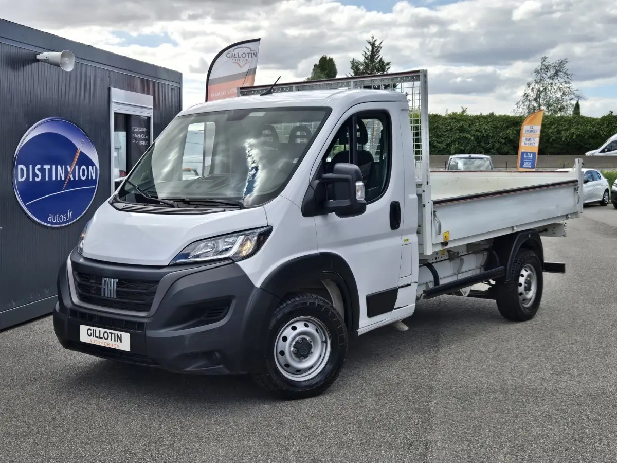 Fiat Ducato Fourgon blanc en vue 3/4 avant droit, plateau arrière ouvert avec grille de protection.