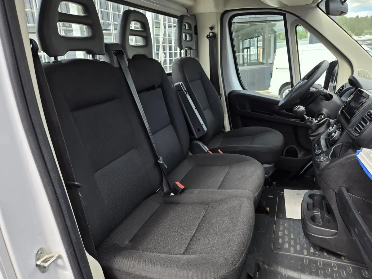 Vue intérieure côté conducteur du Fiat Ducato Fourgon blanc 2022, montrant les sièges noirs et le tableau de bord.