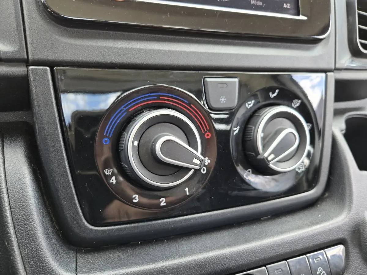Gros plan sur les commandes de climatisation du tableau de bord noir du Fiat Ducato Fourgon blanc 2022.