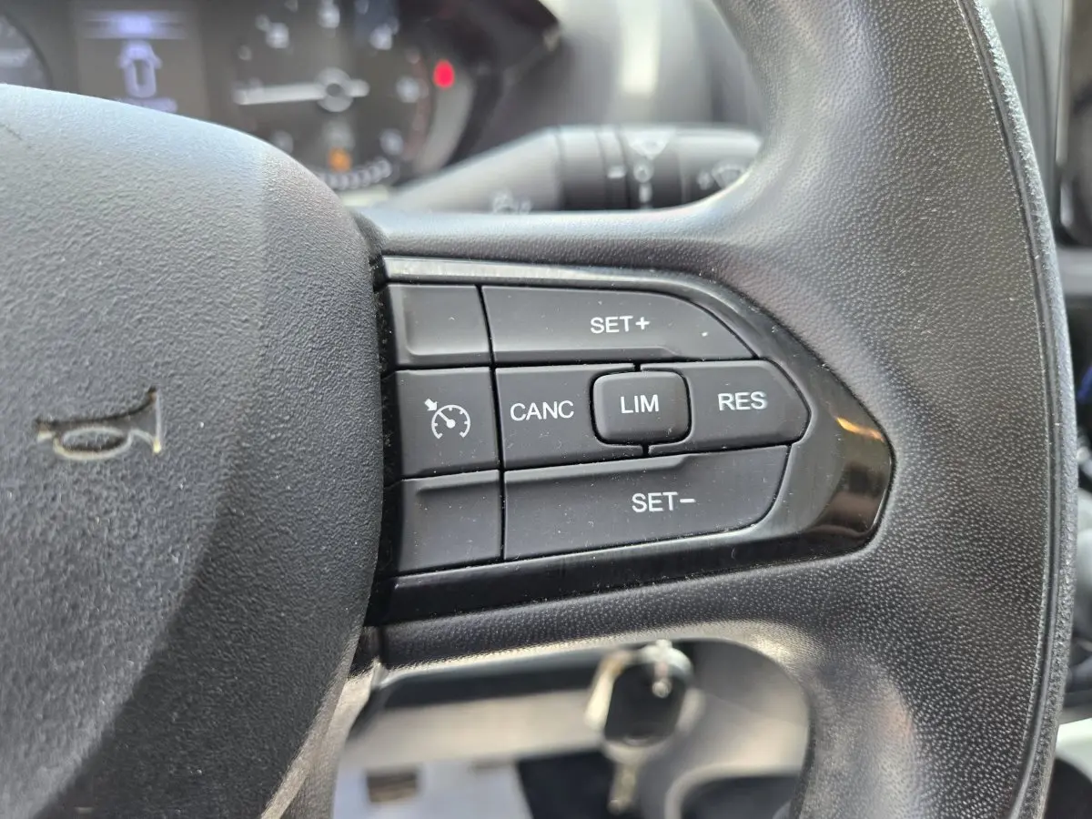 Gros plan sur les commandes du régulateur de vitesse au volant noir du Fiat Ducato Fourgon blanc, version 2022.