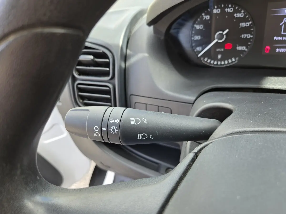 Gros plan sur la commande des phares à gauche du volant dans l’habitacle du Fiat Ducato Fourgon blanc 2022.