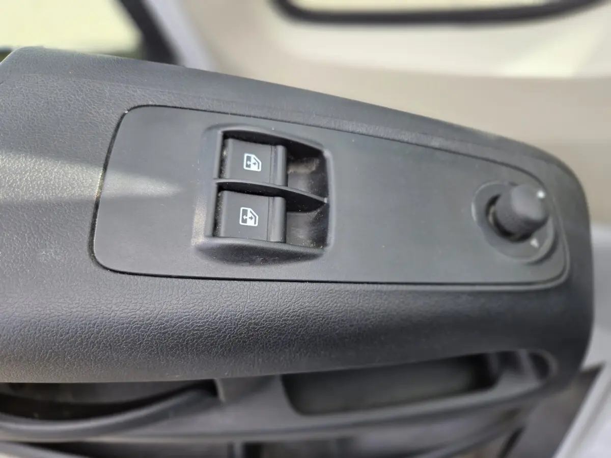 Gros plan sur les commandes de lève-vitres et réglage des rétroviseurs côté conducteur du Fiat Ducato Fourgon blanc 2022.