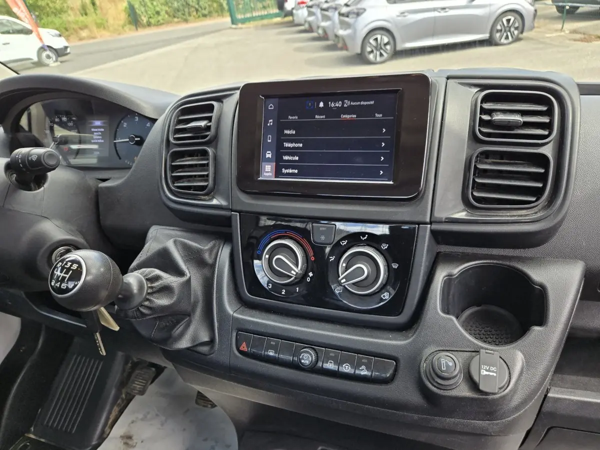 Vue rapprochée du tableau de bord noir du Fiat Ducato Fourgon 2022 avec écran tactile et commande de climatisation.