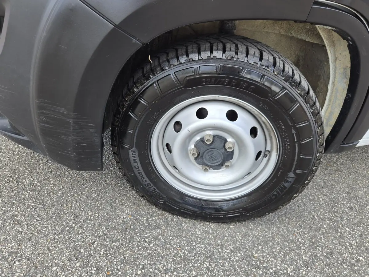 Gros plan sur la roue avant droite du Fiat Ducato Fourgon blanc, avec jante acier et pneu Michelin CrossClimate.
