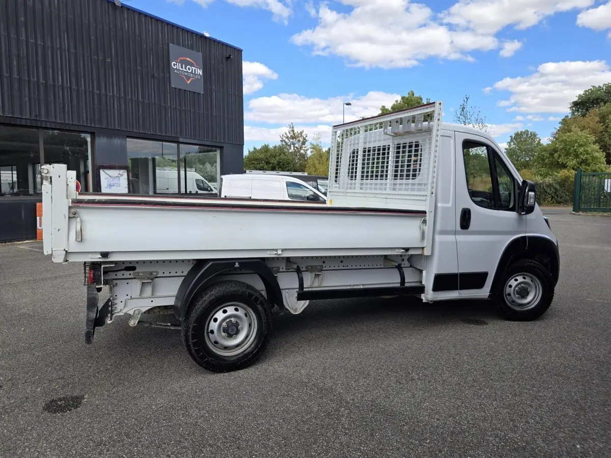 FIAT Ducato Fourgon blanc vu de profil côté droit, plateau arrière avec grille de protection sur cabine.