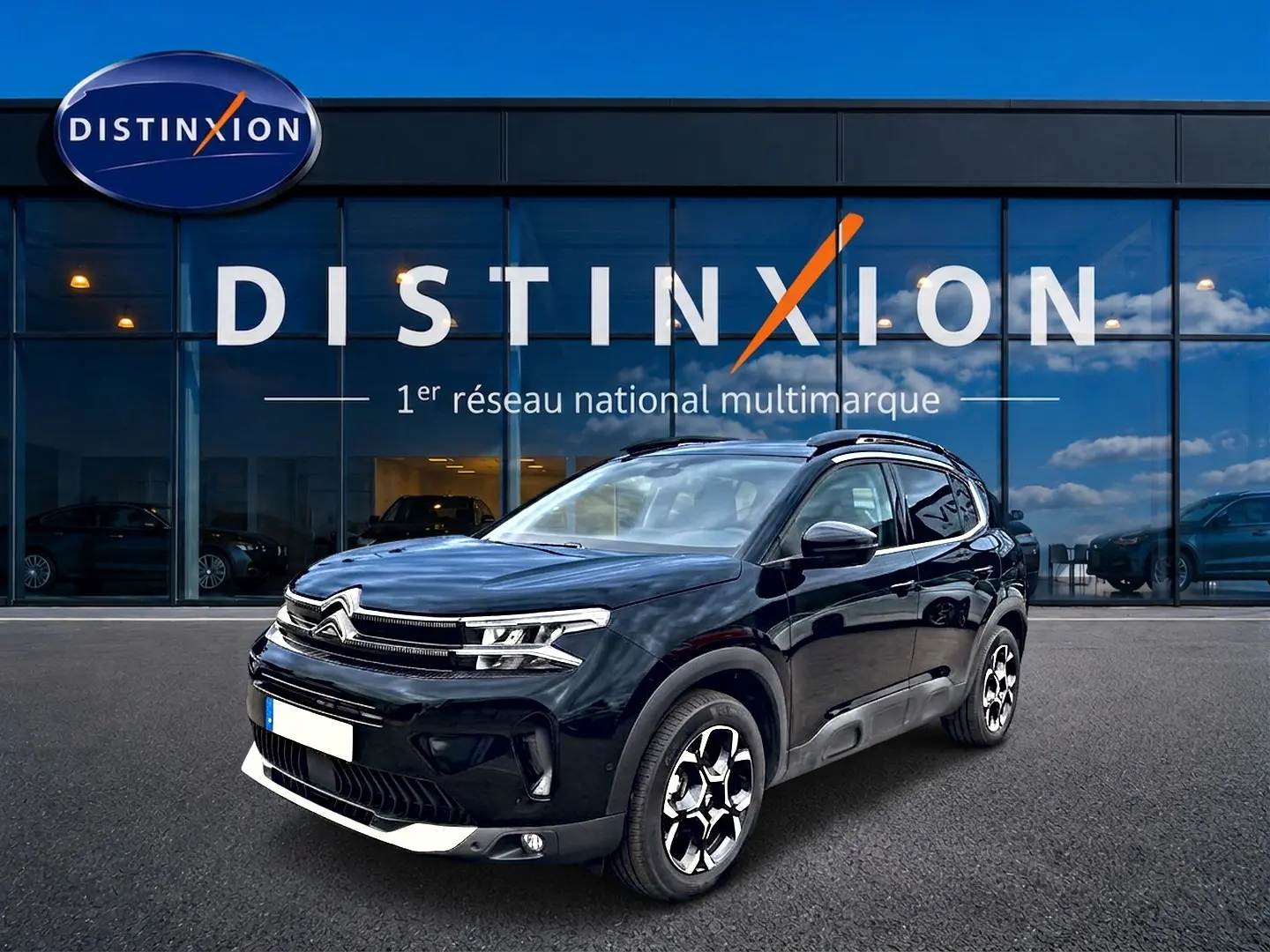 Citroën C5 Aircross noir vue 3/4 avant droit, avec jantes alu et barres de toit visibles devant un showroom Distinxion.