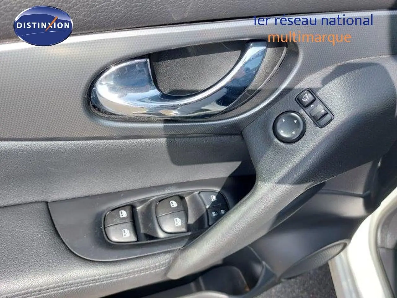 Poignée de porte intérieure côté conducteur du Nissan Qashqai blanc lunaire, avec commandes électriques des vitres et rétroviseurs.