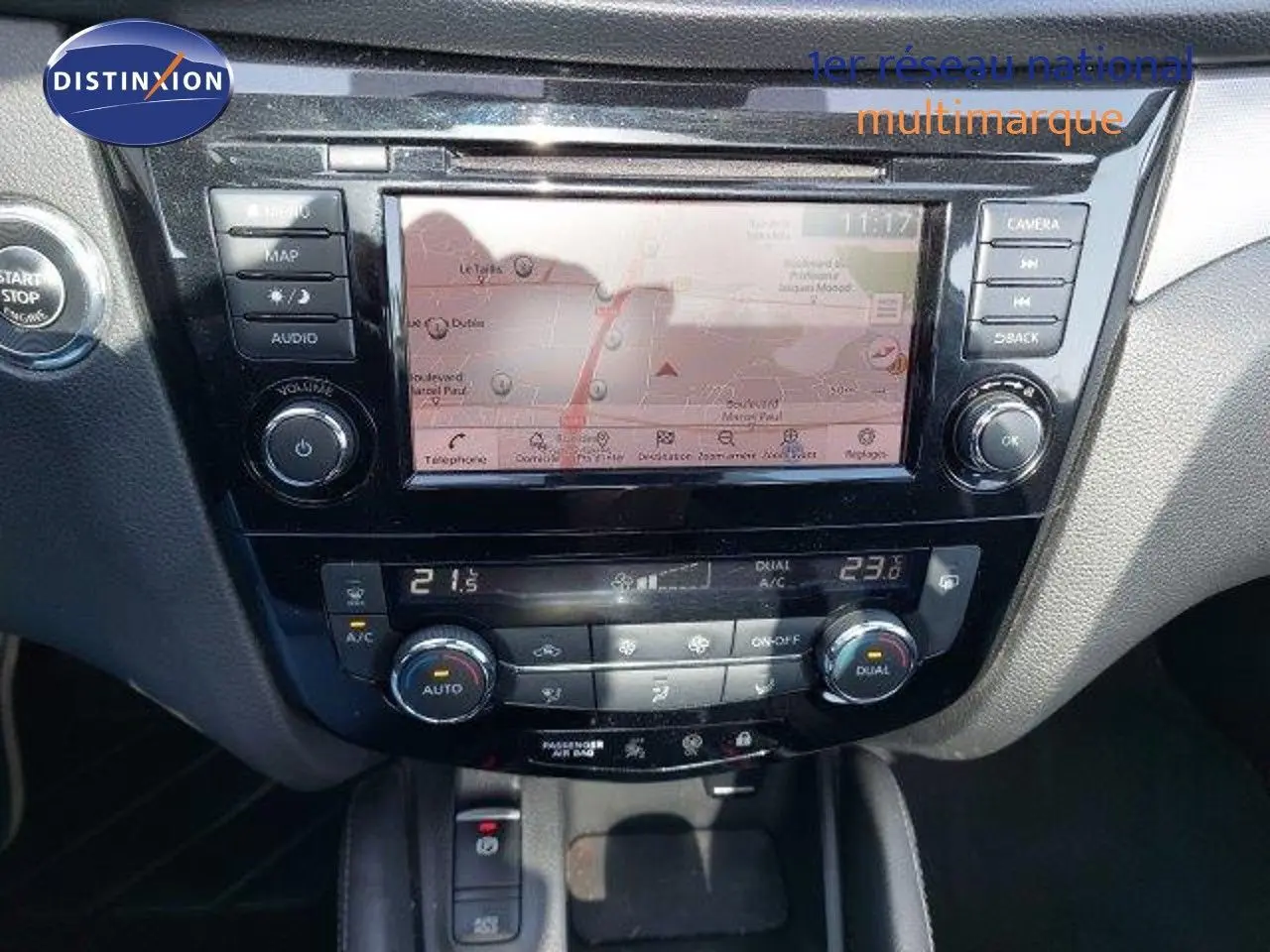 Tableau de bord du Nissan Qashqai blanc lunaire, affichant l'écran tactile central et la climatisation automatique.