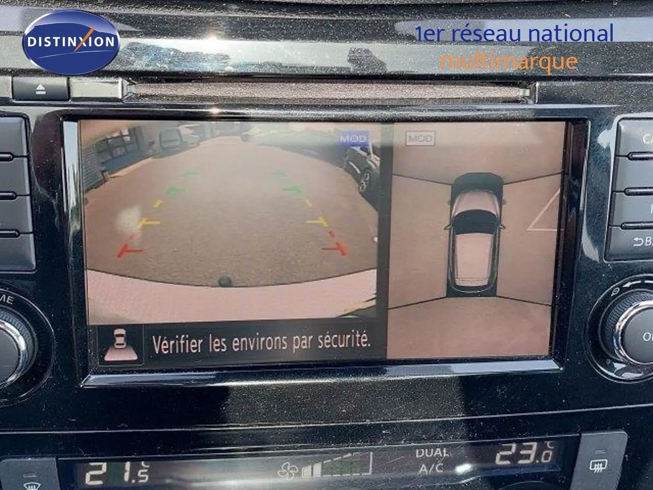 Écran multimédia montrant la caméra de recul et vue 360° du Nissan Qashqai blanc lunaire, tableau de bord en noir brillant.