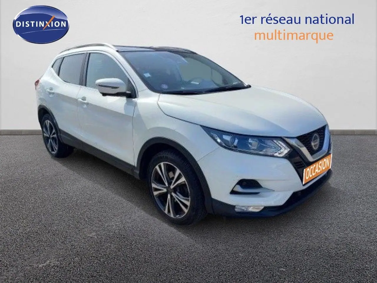 Nissan Qashqai blanc lunaire en 3/4 avant droit, avec jantes alliage bicolores et calandre noire distinctive.