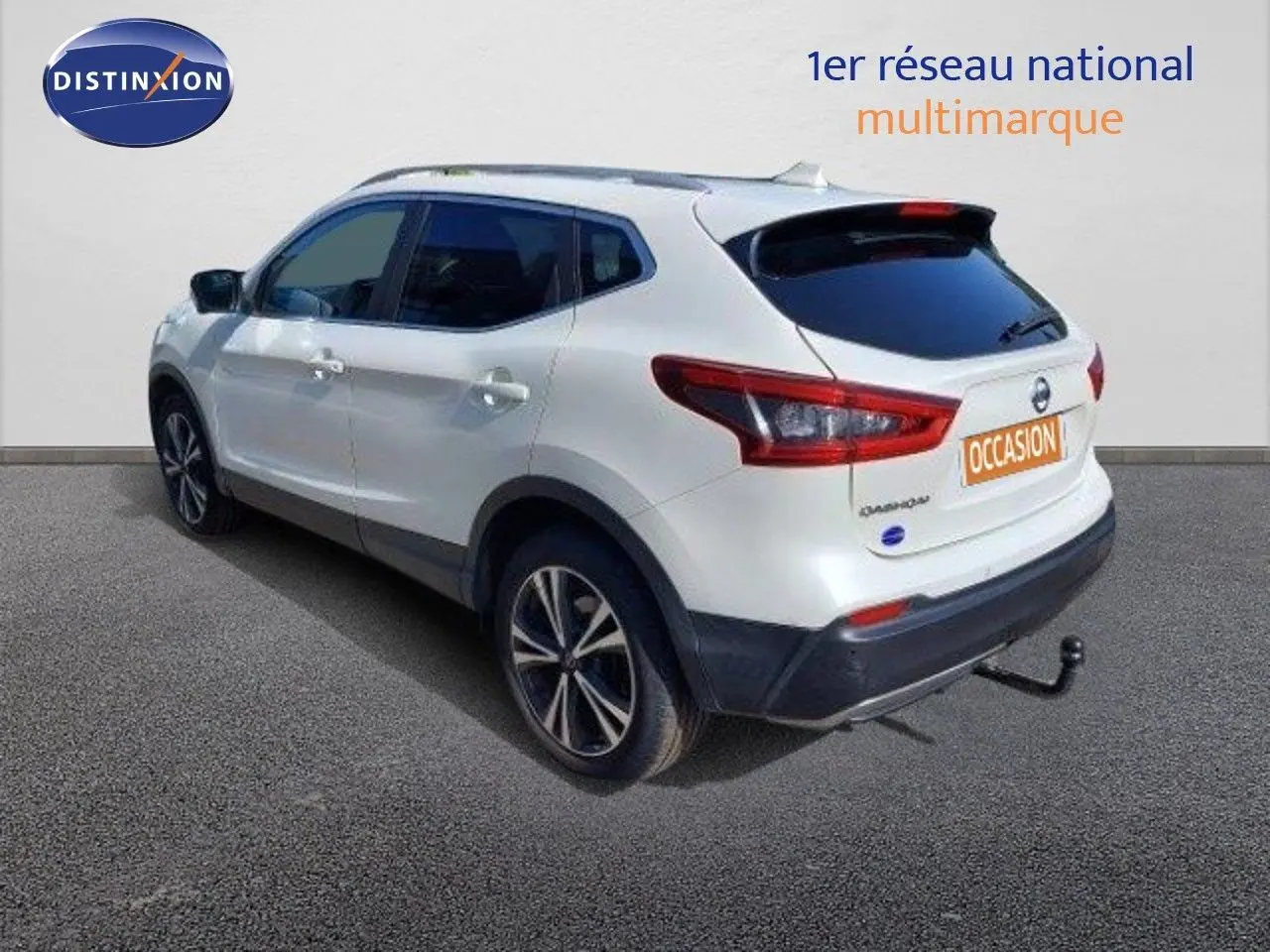 Nissan Qashqai blanc lunaire vu en 3/4 arrière droit avec attelage et jantes biton 18 pouces.