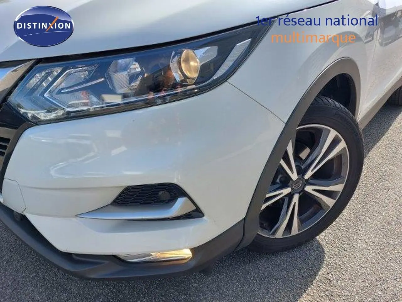 Gros plan sur l'avant droit blanc lunaire métal du Nissan Qashqai 2019 avec phares et jante biton visibles.