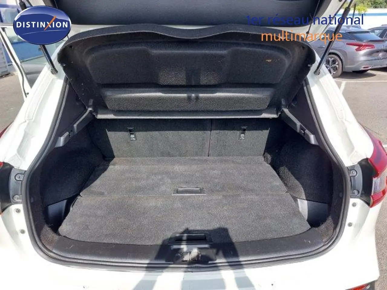 Coffre ouvert vue arrière d'un Nissan Qashqai blanc lunaire métal, montrant l'espace de chargement vide.