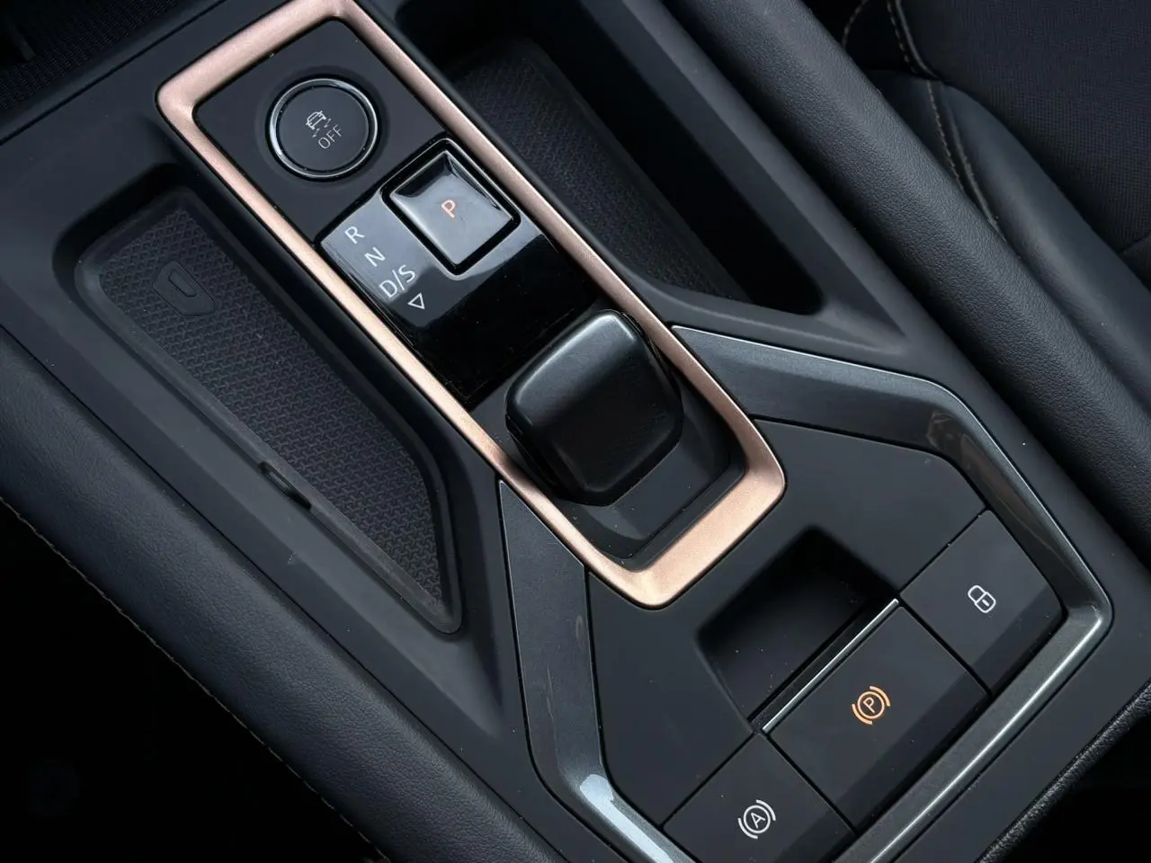 Gros plan sur la console centrale noire et cuivre avec commandes de boîte auto et frein à main électrique de la CUPRA Leon 2025.