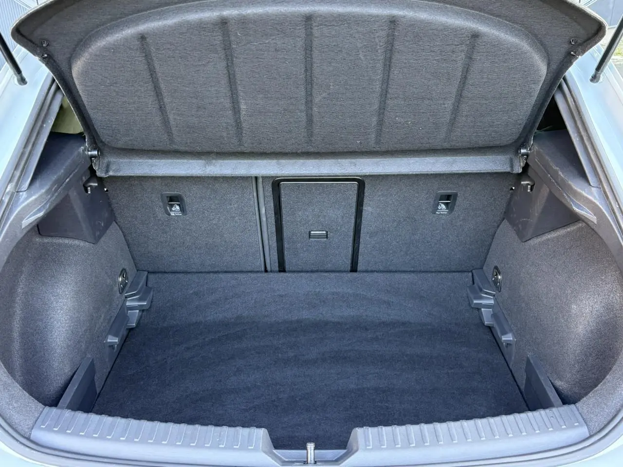 Vue intérieure du coffre ouvert de la CUPRA Leon 2025, montrant un espace de rangement propre et tapissé en tissu gris.