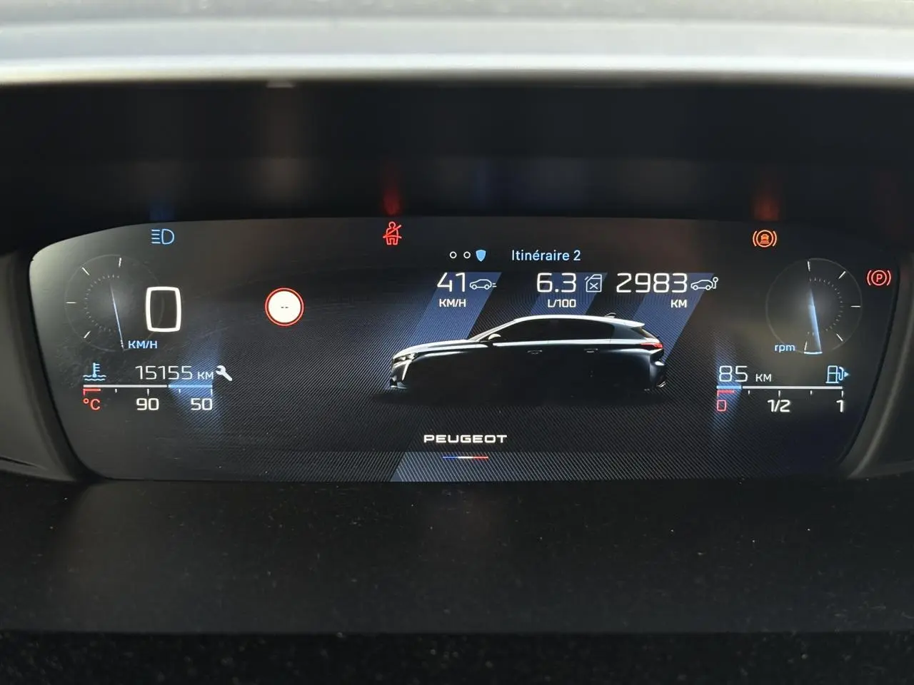 Combiné numérique 10 pouces de Peugeot 308 2024 affichant vitesse, consommation et autonomie avec silhouette du véhicule en profil.