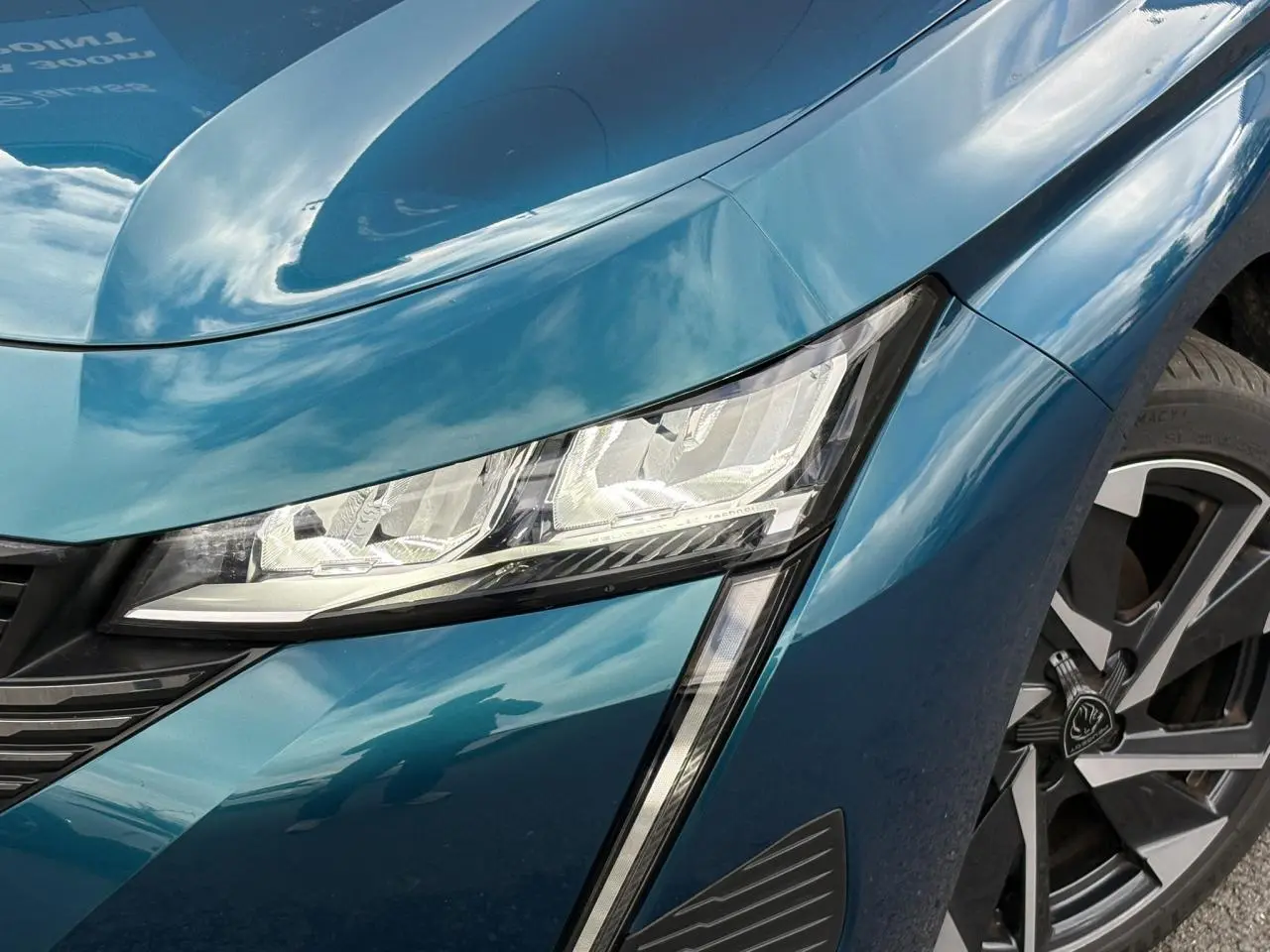 Gros plan sur le phare avant droit et la jante alliage 17'' d’une Peugeot 308 Bleu Obsession 2024.