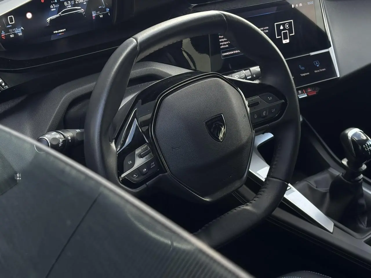 Vue rapprochée du volant cuir noir et du levier de vitesse manuel dans l’habitacle d’une Peugeot 308 2024.