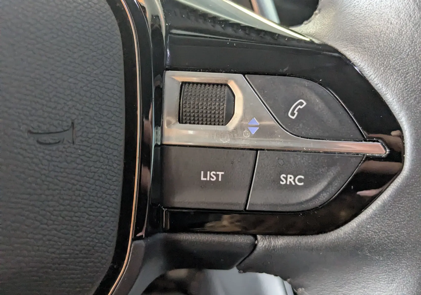 Gros plan sur les commandes gauche du volant noir du Peugeot 2008 1.5 BlueHDi 130, boutons LIST, SRC et téléphone.