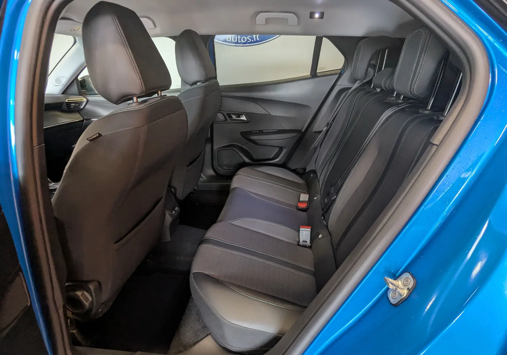 Vue intérieure côté droit sur les sièges arrière noirs d'une Peugeot 2008 bleu 2022, finition Allure.
