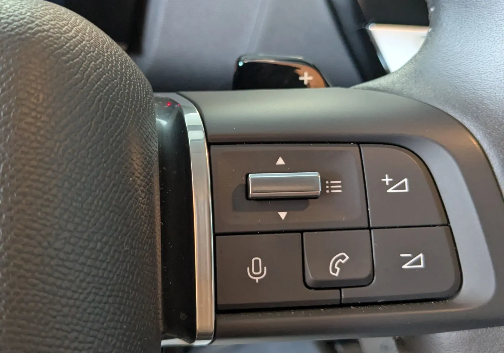 Gros plan sur les commandes au volant côté gauche du Citroën C4 Hybrid 145 gris Mercury, boutons multifonctions visibles.