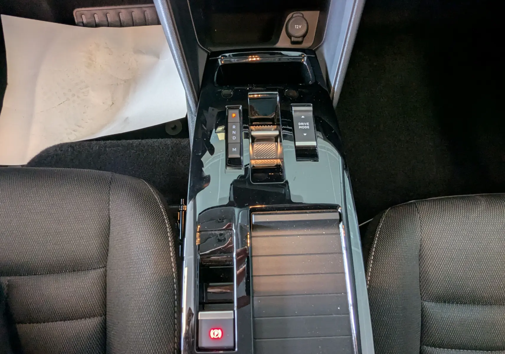 Vue plongeante sur la console centrale noire brillante de la Citroën C4 Hybrid 145, avec levier de vitesses et boutons visibles.