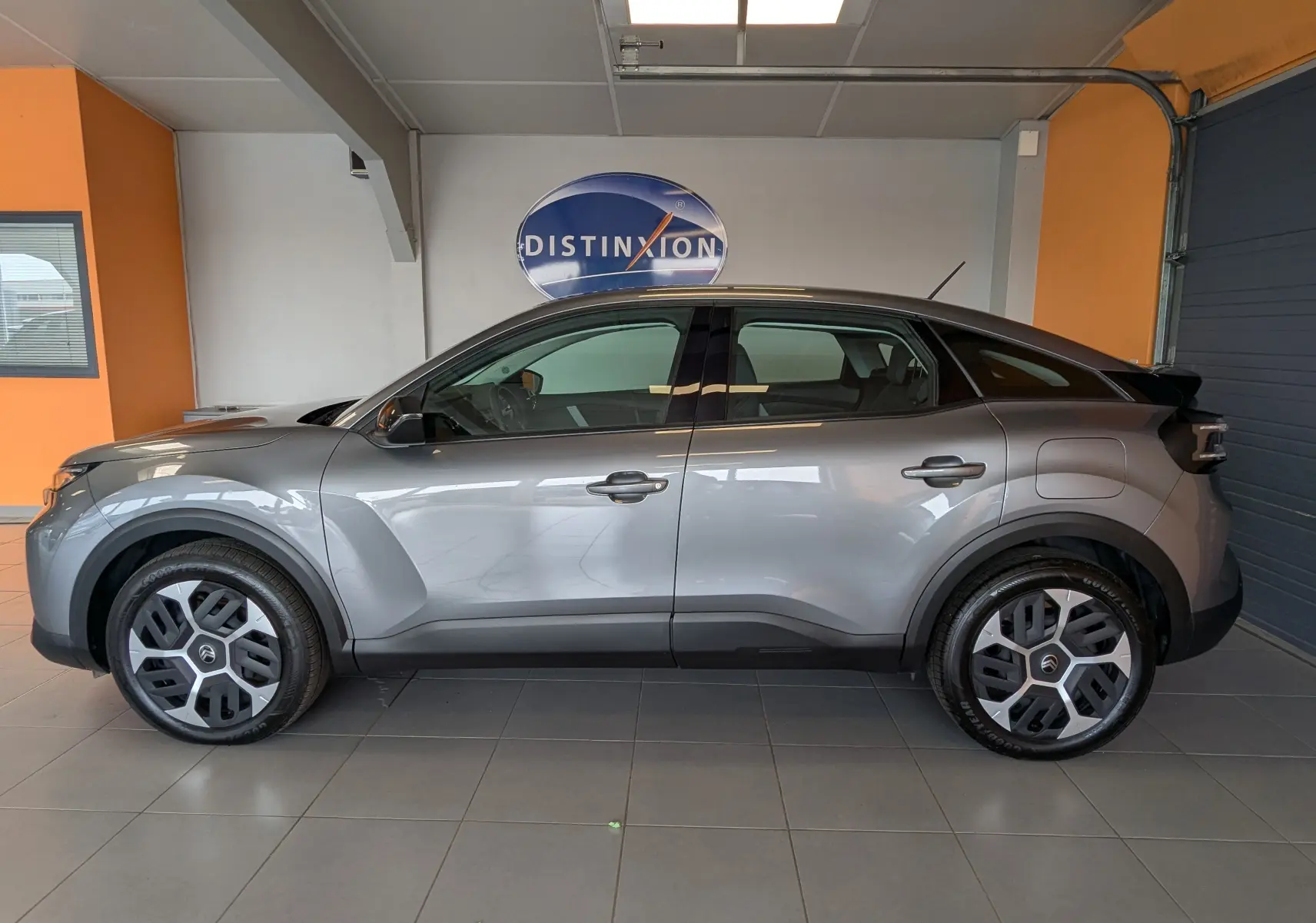 Vue de profil côté gauche d'une Citroën C4 Hybrid 145 E-DCS6 Plus gris Mercury, avec jantes tôles 18 pouces et poignées de porte intégrées.