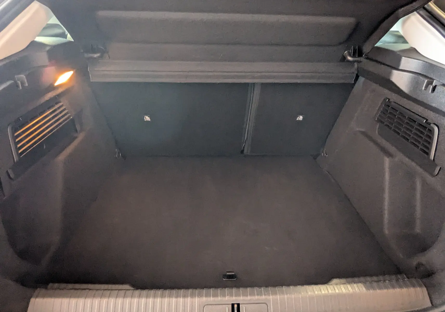 Coffre ouvert de la Citroën C4 Hybrid 145 gris Mercury, montrant un espace de chargement propre et éclairé à gauche.