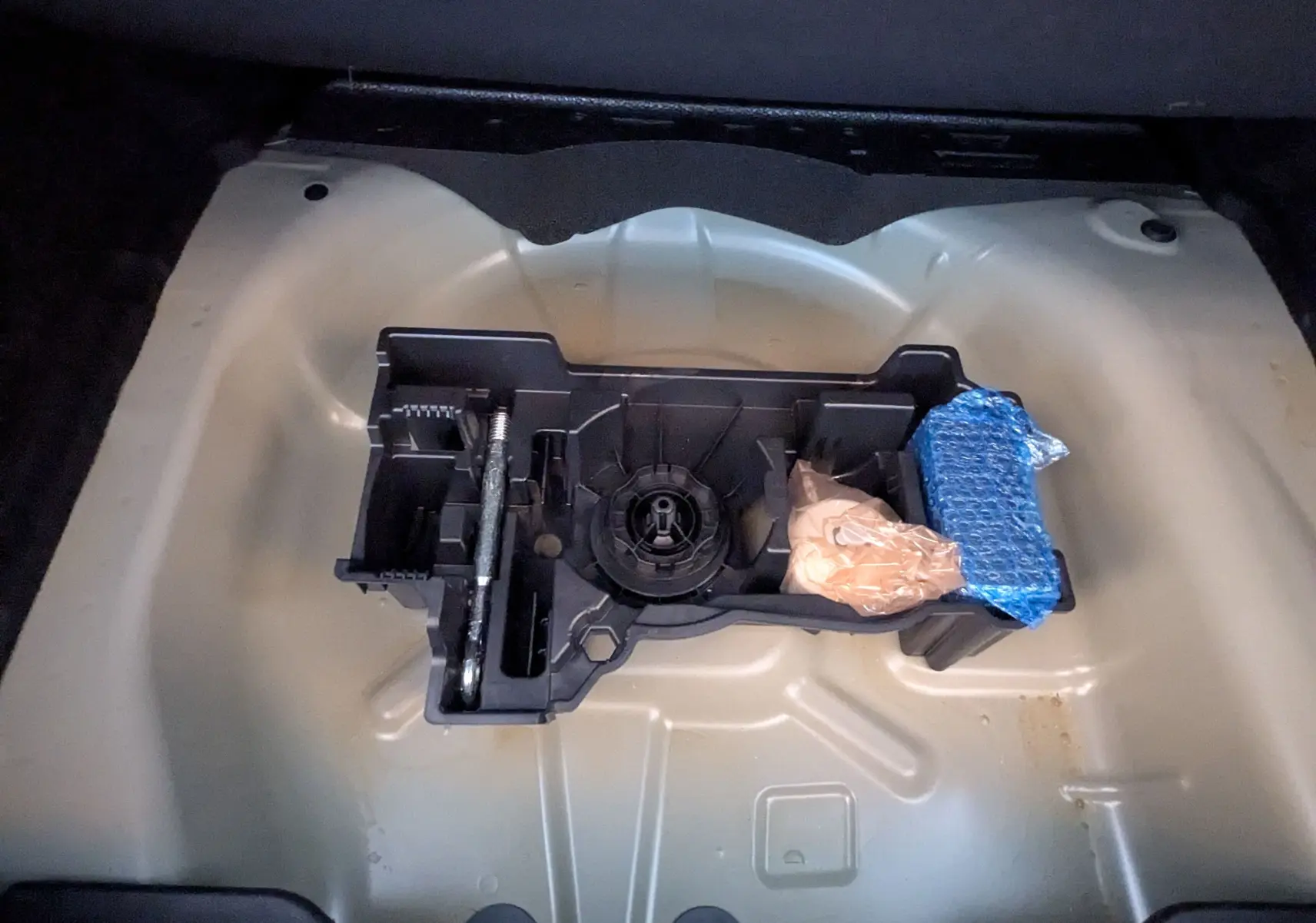 Vue rapprochée du rangement sous le coffre d'une Citroën C4 gris Mercury, montrant un support d'outils et accessoires.