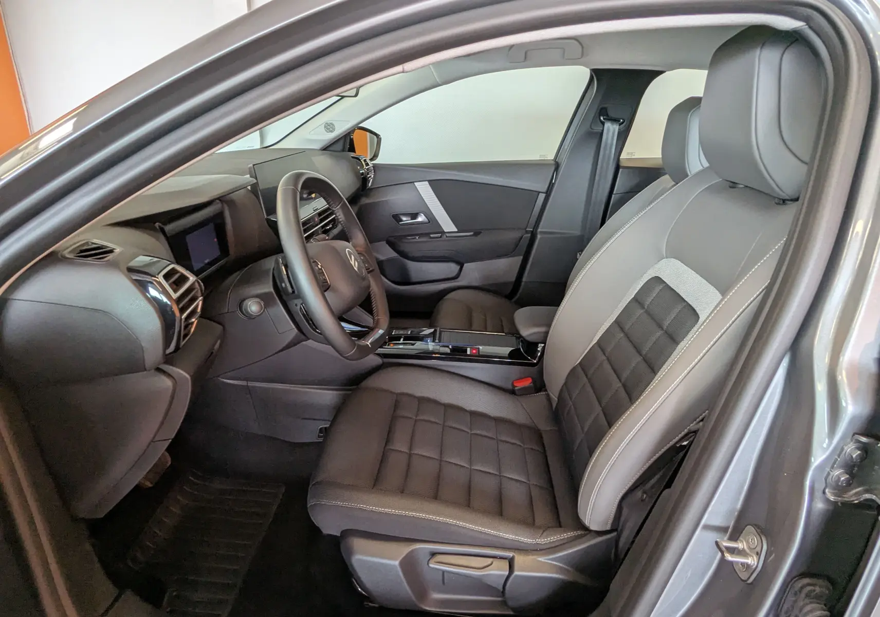 Intérieur côté conducteur d'une Citroën C4 Hybrid 145 gris Mercury, sièges tissu/TEP et tableau de bord moderne.