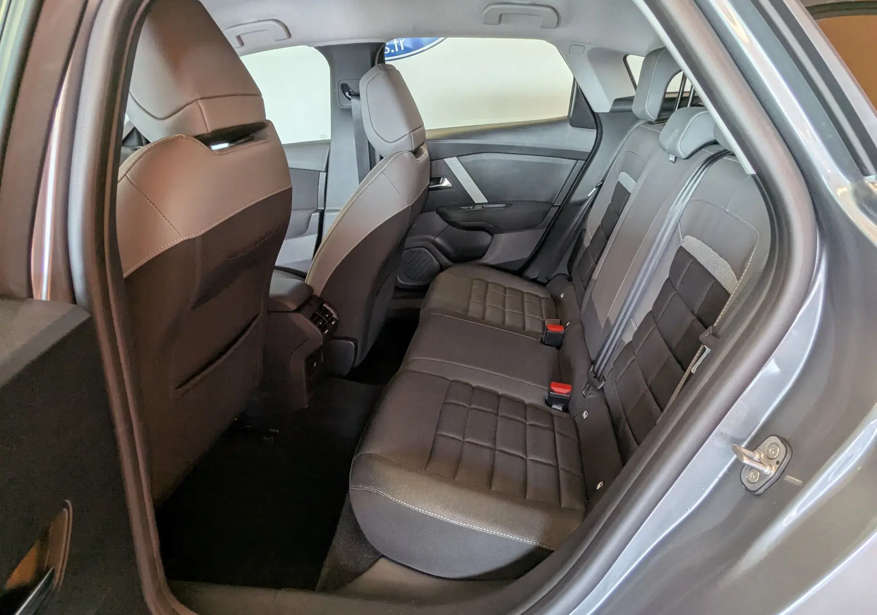 Vue intérieure arrière droite de la Citroën C4 Hybrid 145 gris Mercury, montrant les sièges tissu/TEP et les ceintures de sécurité.