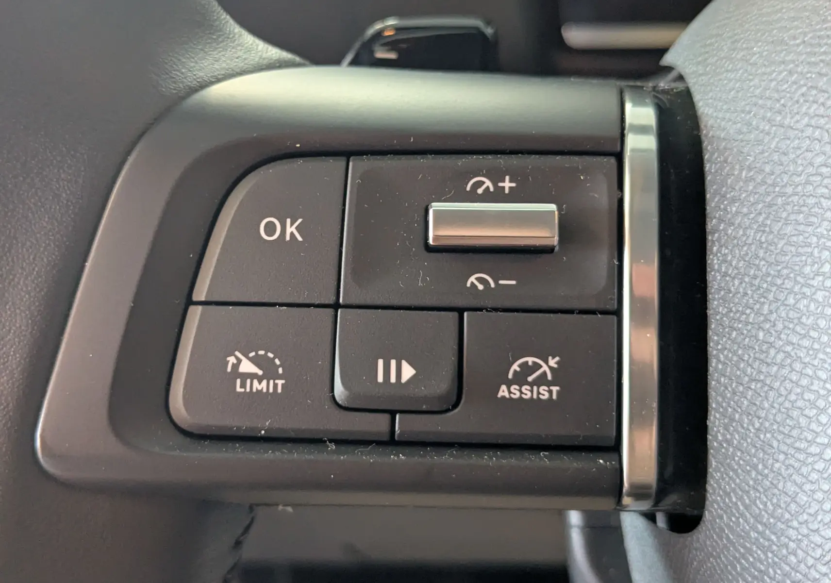 Gros plan sur les commandes au volant du Citroën C4 Hybrid 145 gris Mercury, boutons de régulateur et limiteur de vitesse.