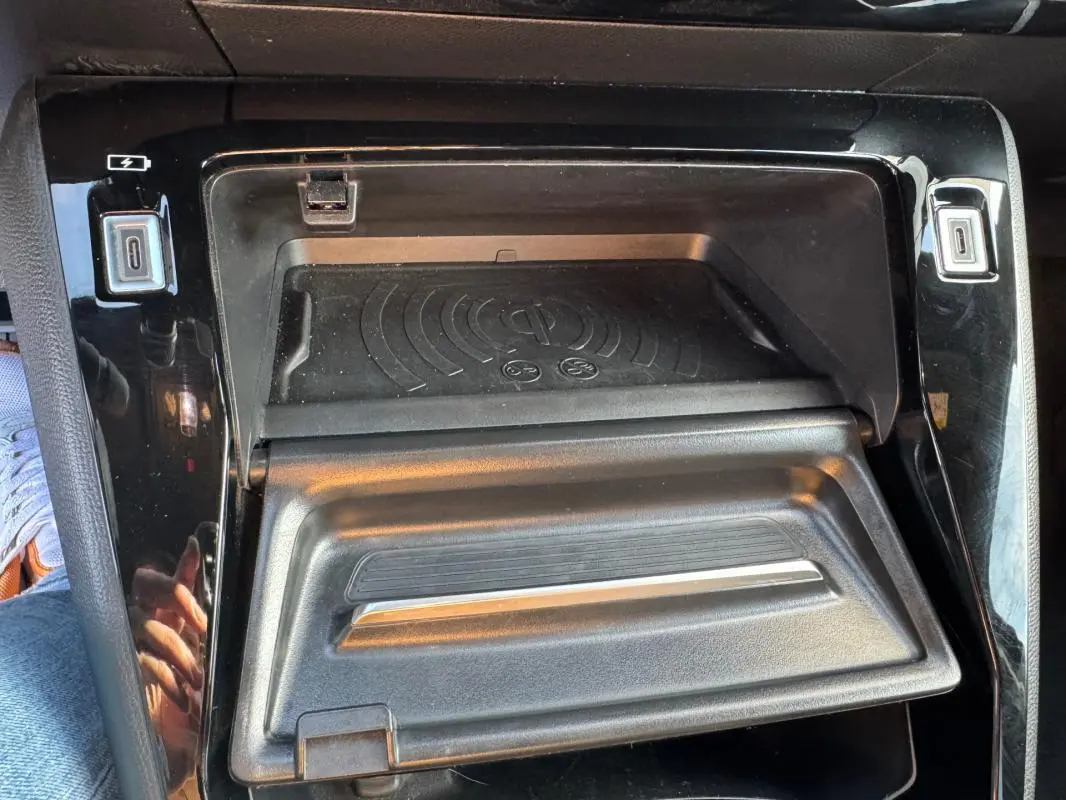 Gros plan sur la console centrale noire du Peugeot 2008 Hybrid 136 e-DCS6 Allure avec compartiment de rangement ouvert.