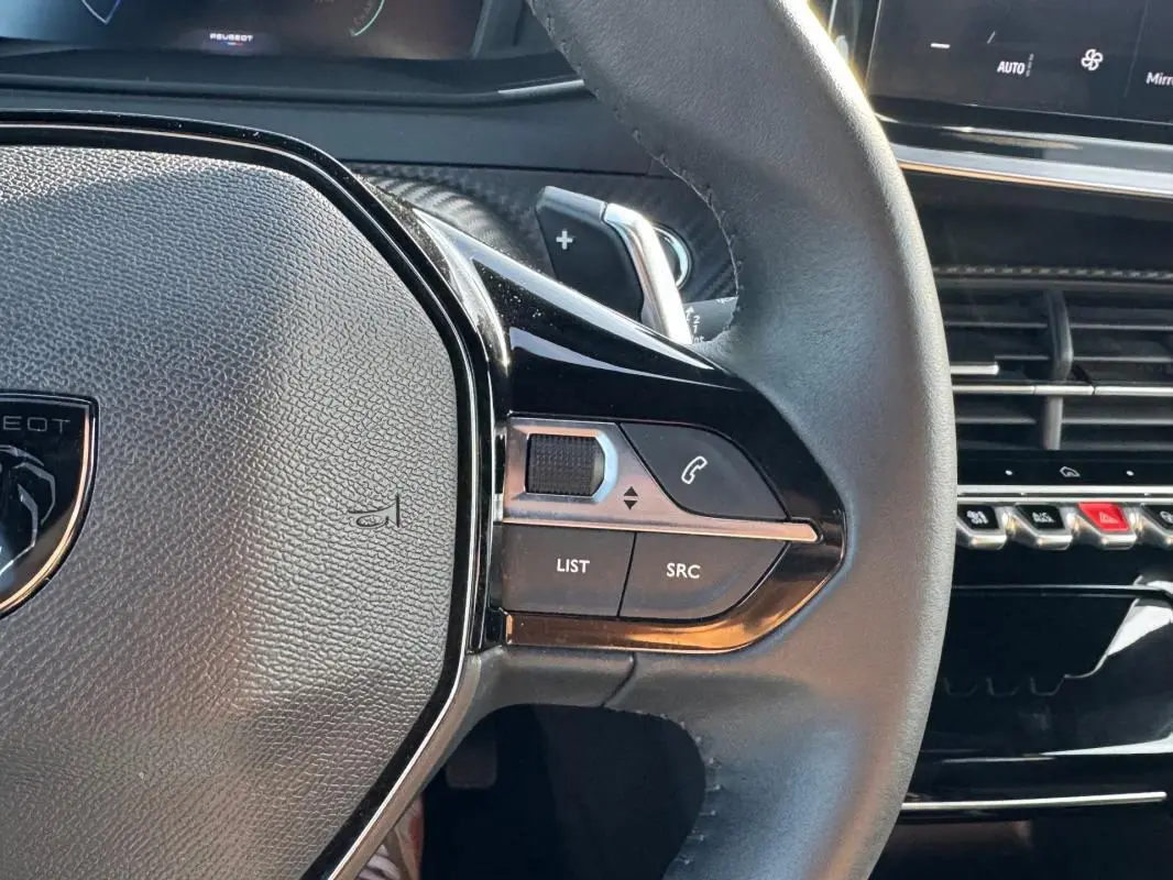 Gros plan sur le volant noir du Peugeot 2008 Hybrid 136 e-DCS6 Allure avec commandes intégrées et partie du tableau de bord.
