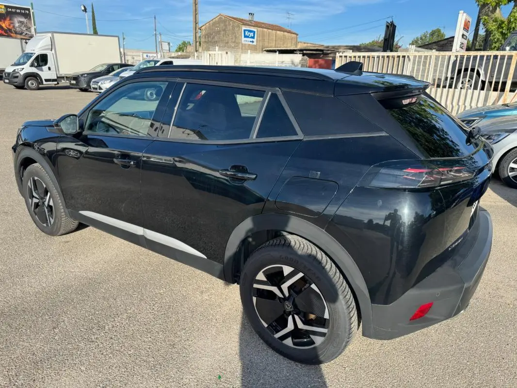 Peugeot 2008 Hybrid noir en 3/4 arrière droit, avec barres de toit et jantes alliage 17 pouces visibles.