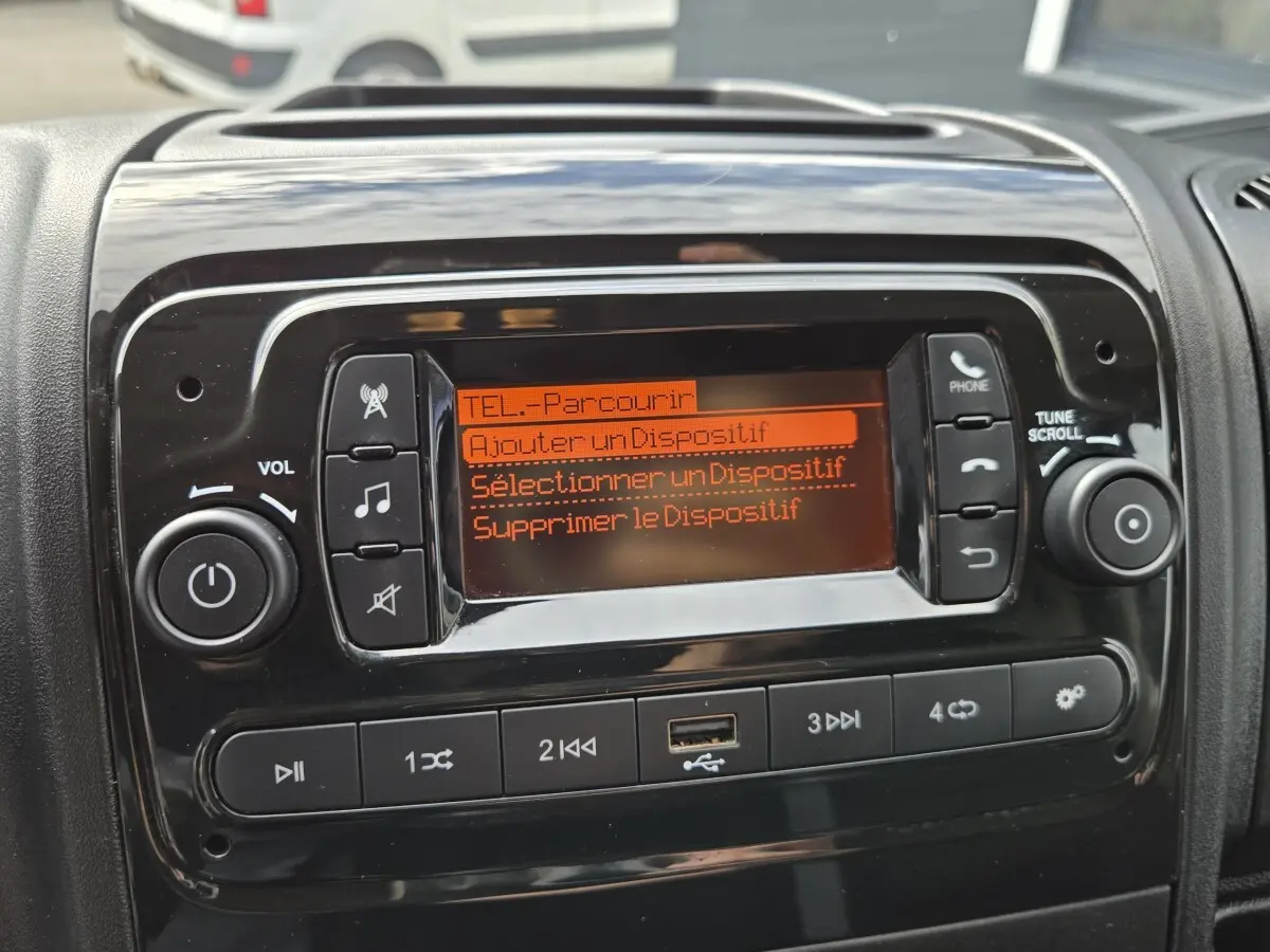 Gros plan sur l’écran central noir brillant du Fiat Ducato Fourgon blanc, affichant le menu téléphone en orange.